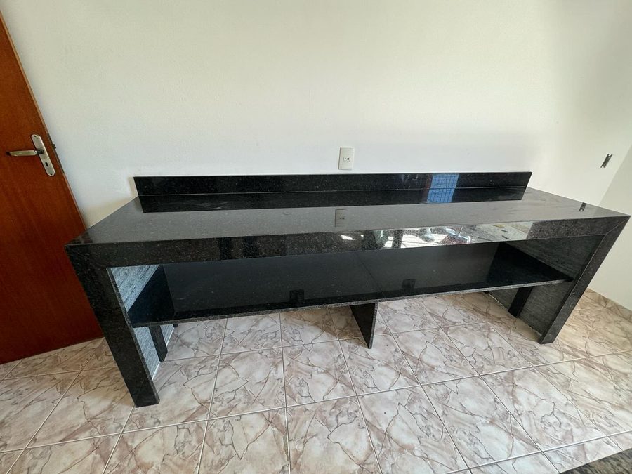 Bancada seca em granito preto com prateleira inferior, encostada na parede